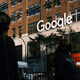A photo of a shadowed-out person with a mask walking by the Google headquarters in NYC